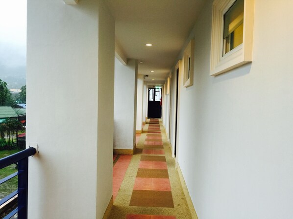 A corridor with a checkered floor pattern, white walls, and a window on the right.