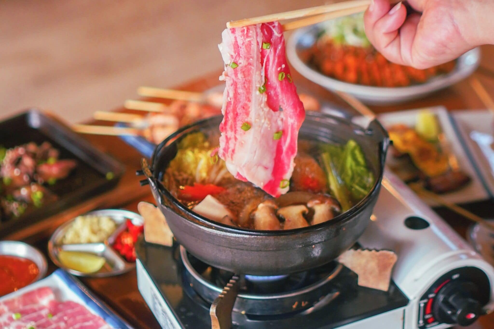 Una olla caliente con diversos ingredientes, incluyendo carne y verduras, en proceso de cocción.