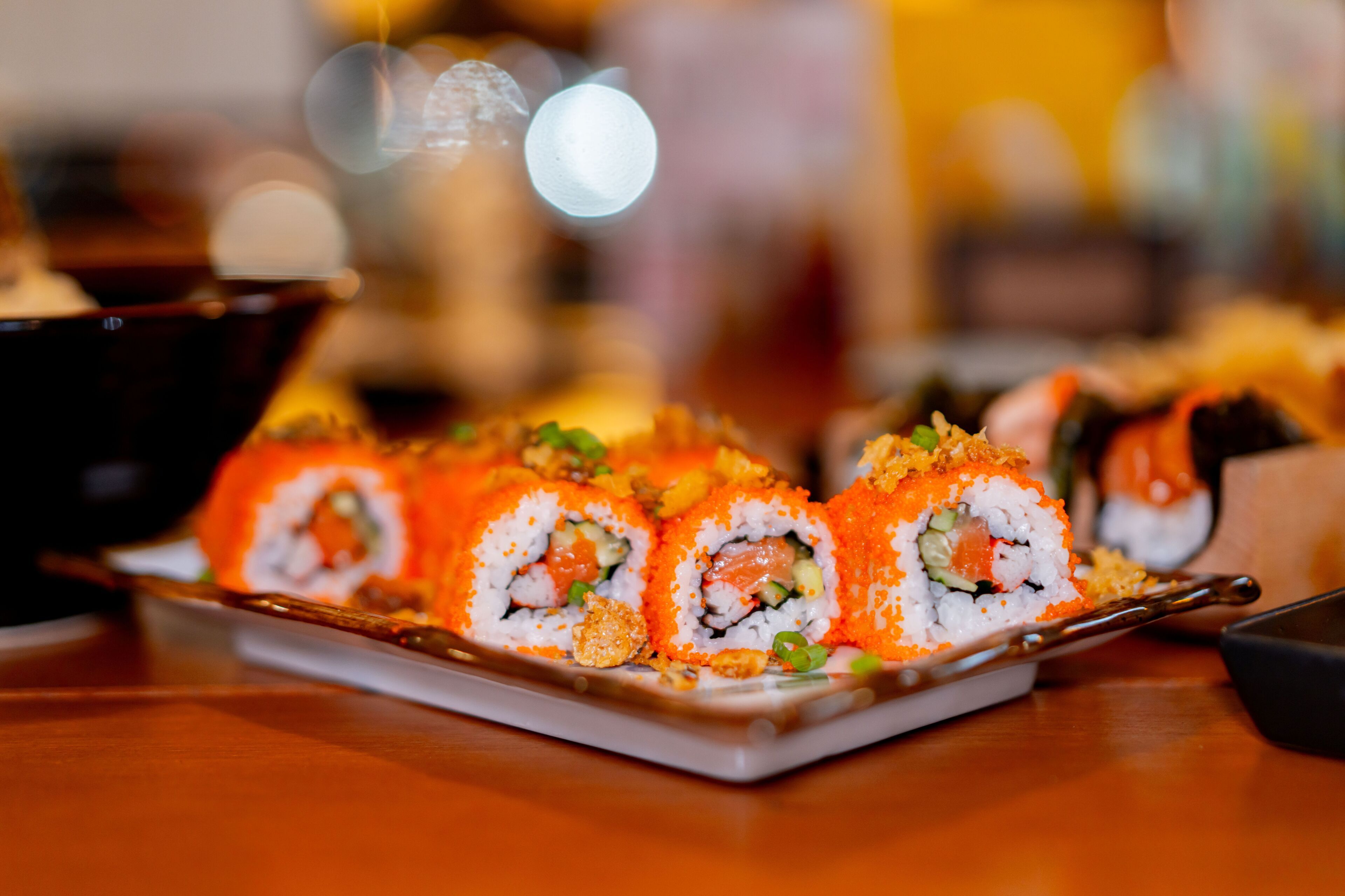 Un plato de rollos de sushi con diferentes rellenos, como salmón y aguacate, sobre una mesa de madera.
