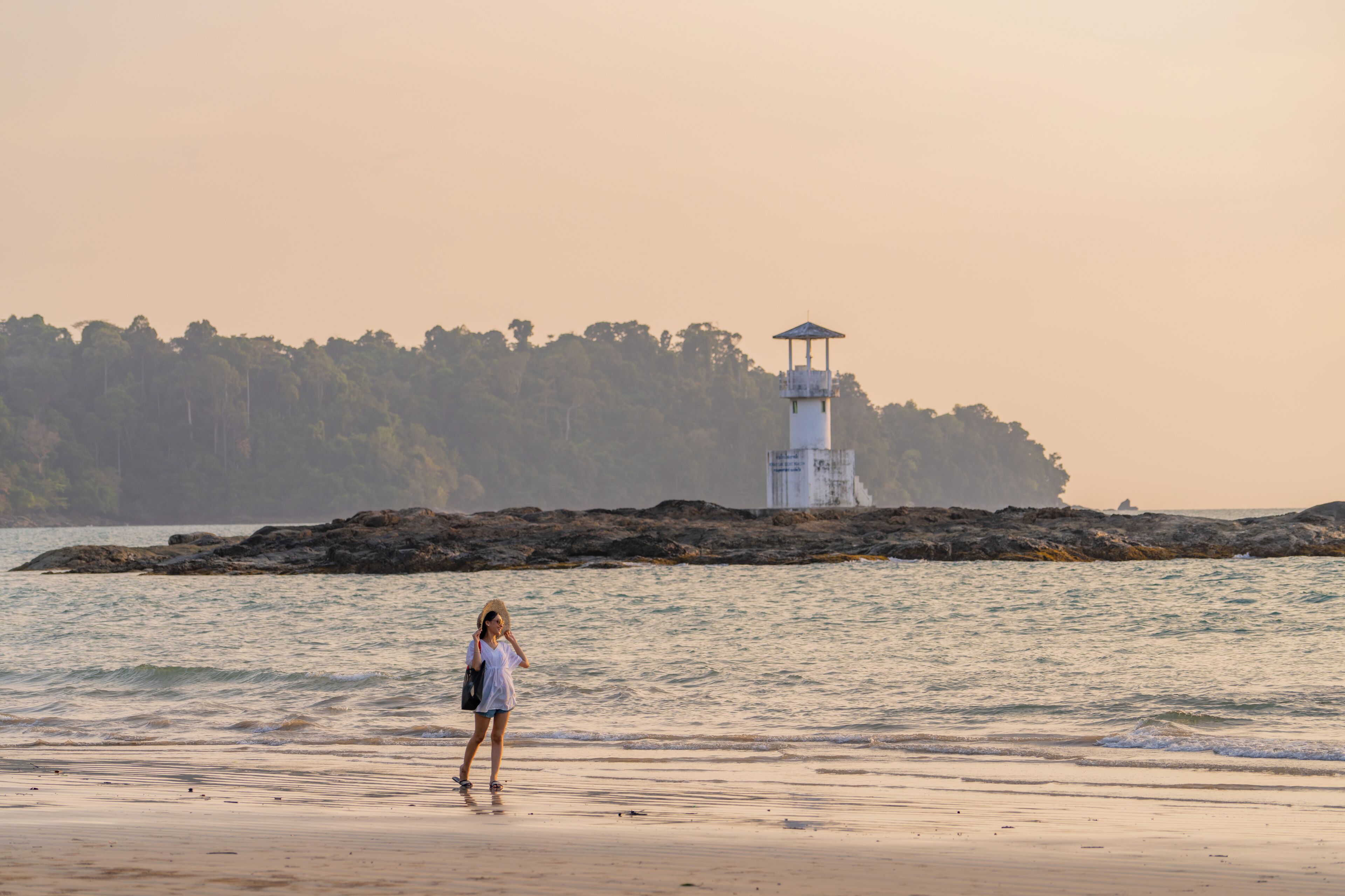 A beach with a lighthouse in the background.