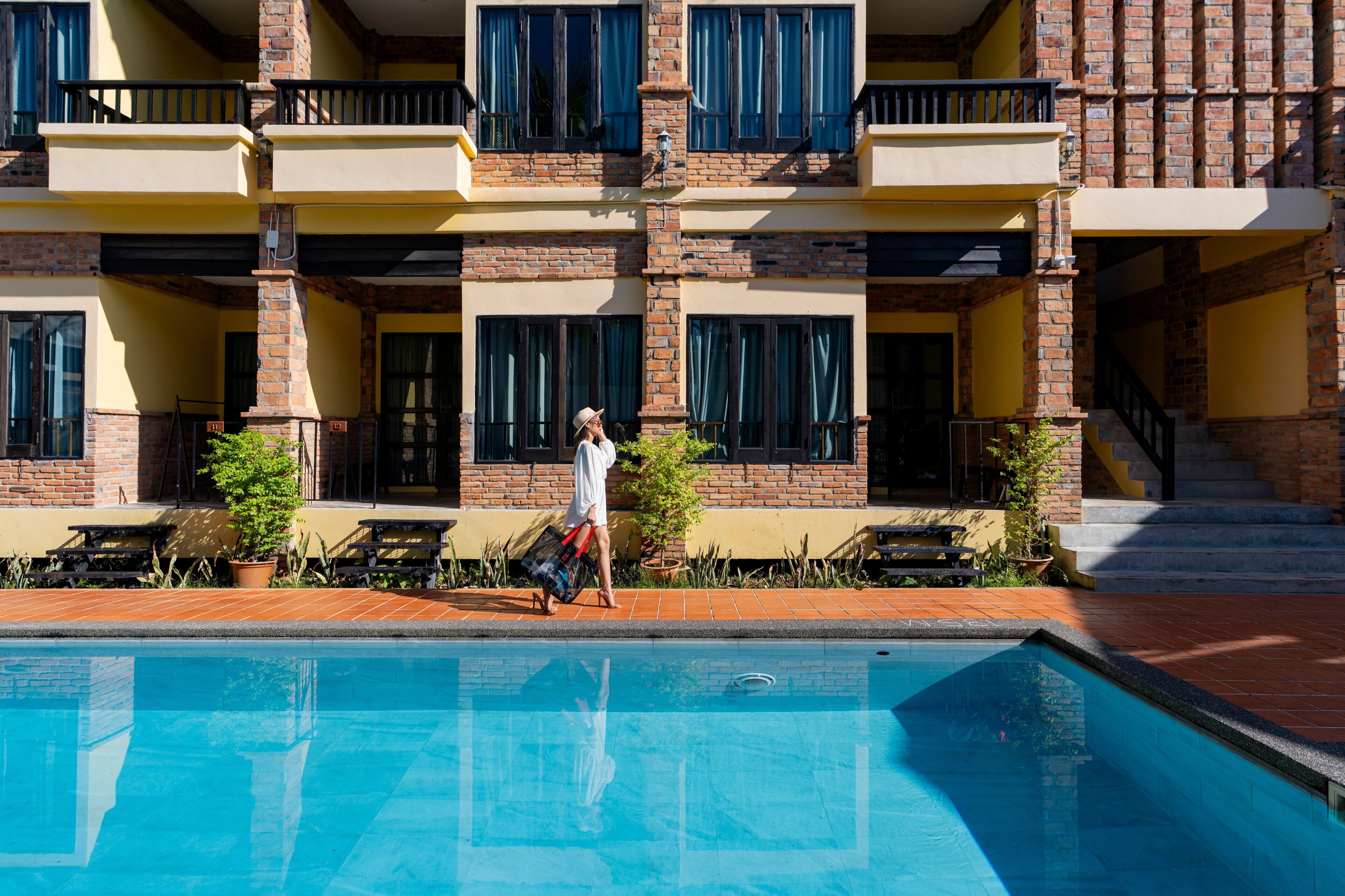 A hotel with a pool, outdoor seating, and a brick facade.