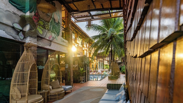 A cozy lounge area with wicker furniture, a pool, and a view of the street. - Motive Cottage Resort (Takua Pa)