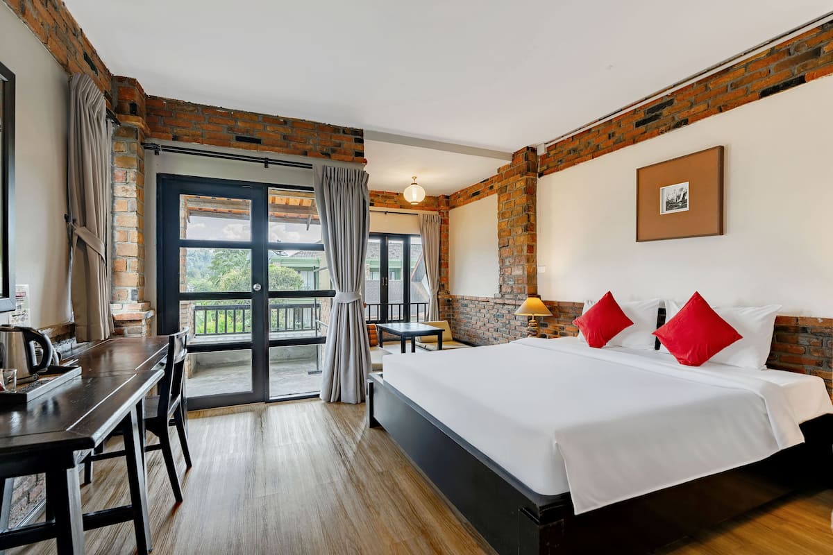 A hotel room with a bed, a desk, and a balcony.