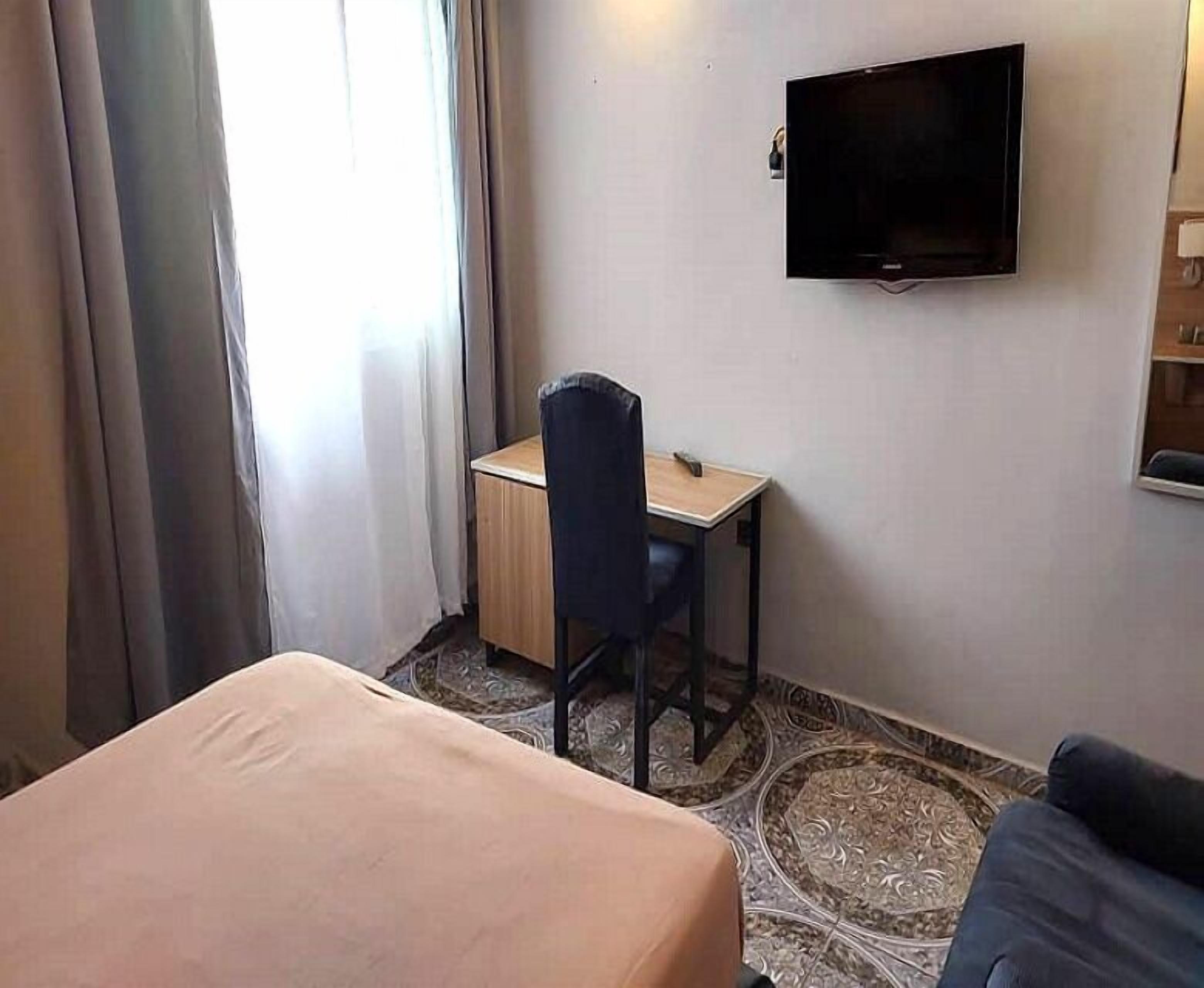 Una habitación de hotel con cama, escritorio y televisión en la pared.