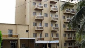 A multi-story hotel with balconies, a bar, and a covered parking area. - Hotel Meumi Palace (Yaoundé)