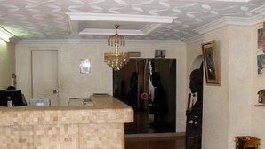 A room with a tiled kitchen counter, a chandelier, a framed picture on the wall, and a door leading to another room. - Hotel Meumi Palace (Yaoundé)