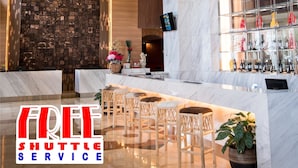 Zona de bar moderna con encimera de mármol, taburetes y una pared decorativa con diseño de mosaico.