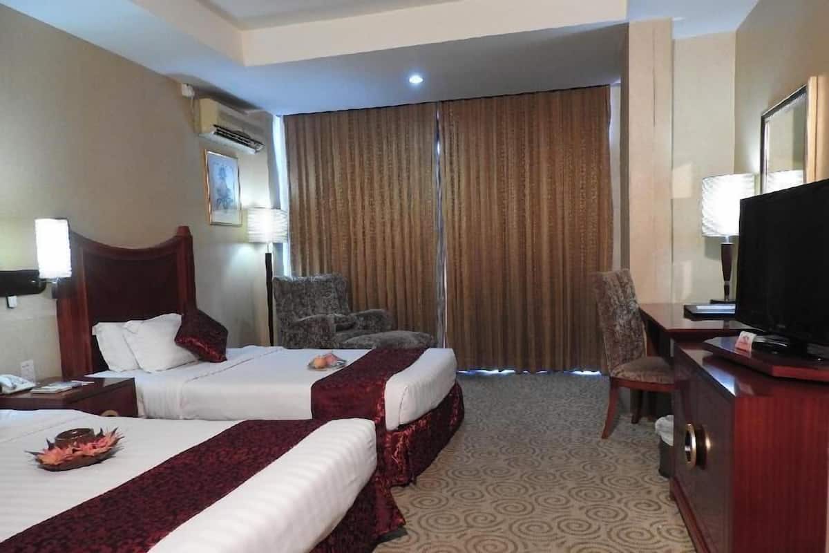 A hotel room with two beds, a television, a desk, and a chair.