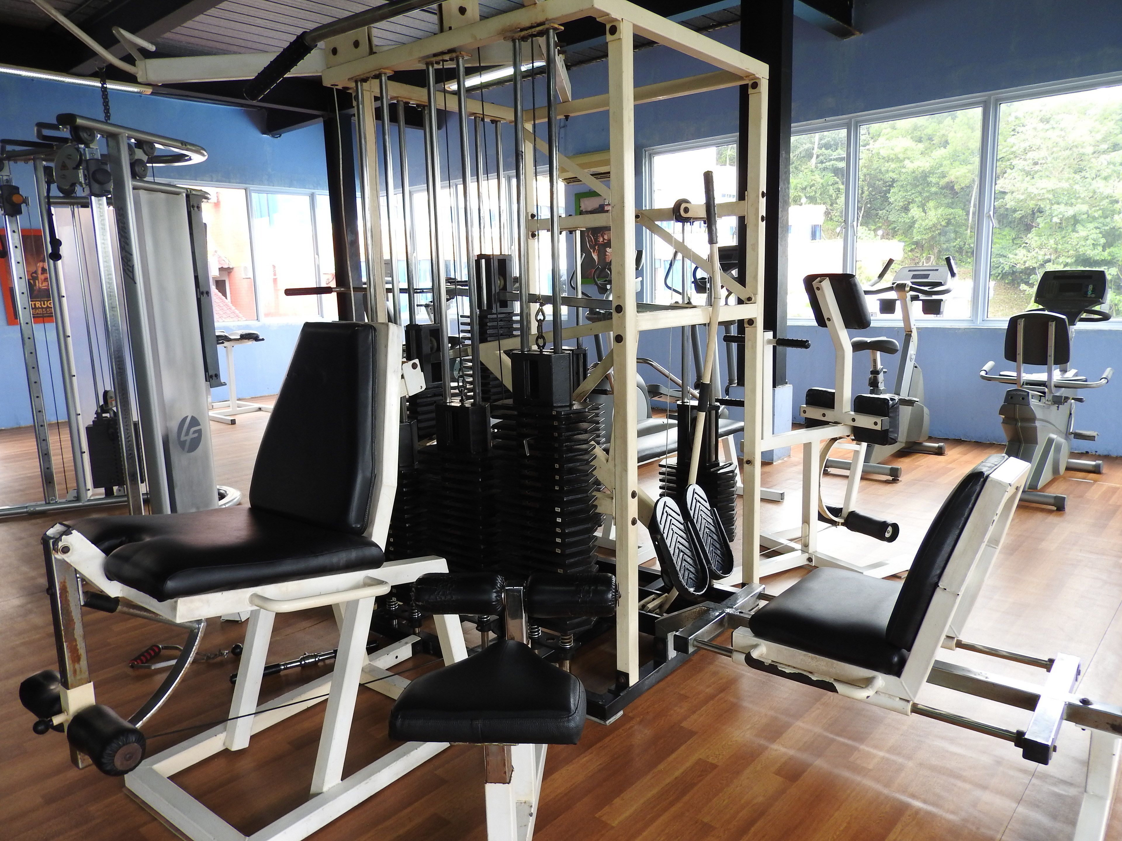 Une salle de sport équipée de divers appareils d’entraînement, notamment des appareils de musculation et des appareils de cardio.