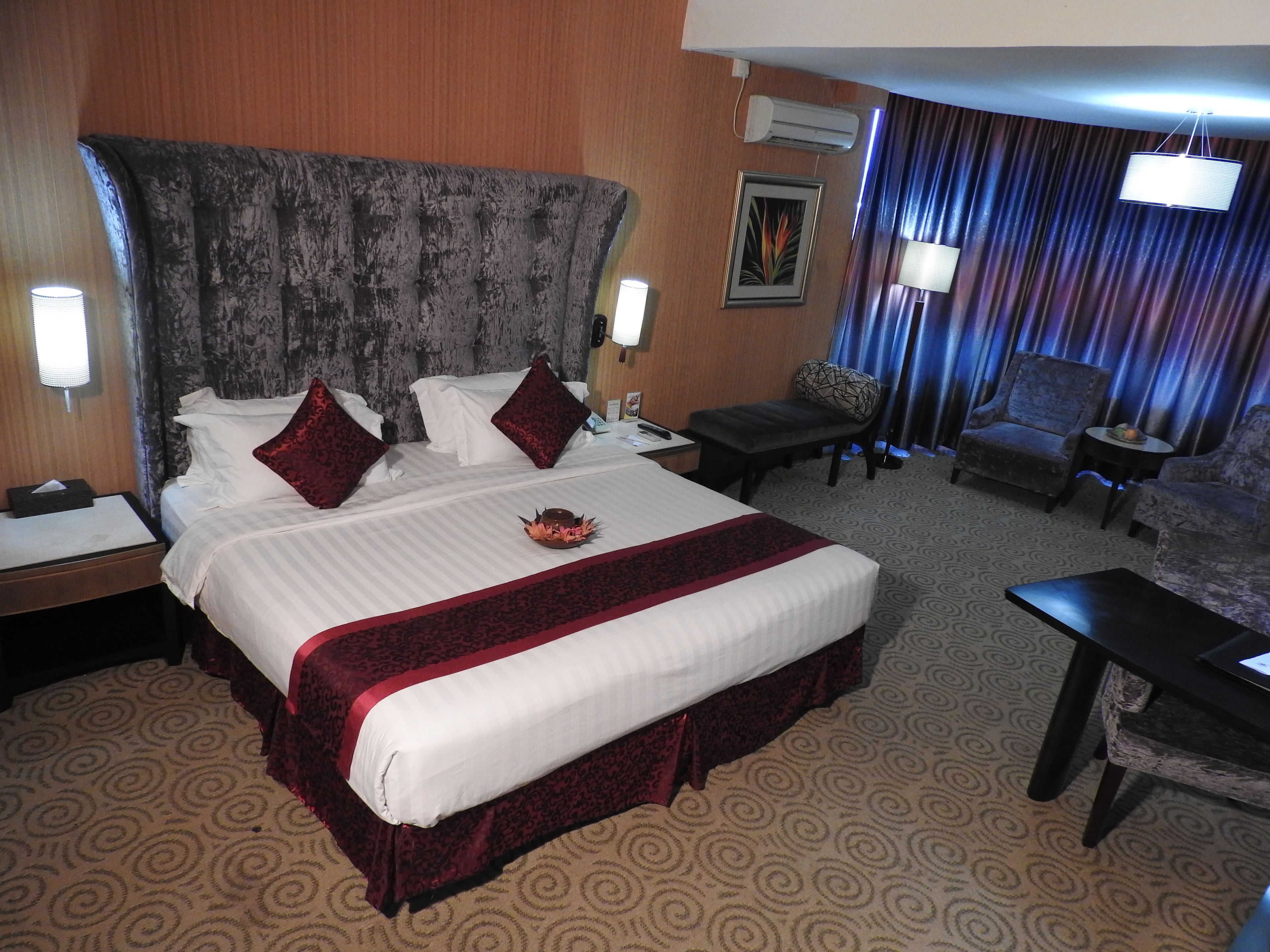 A hotel room with a large bed, a desk, a chair, and a small table.