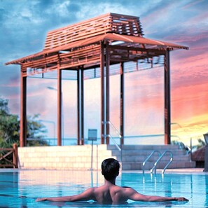 A man in a swimming pool with a wooden structure in the background. - Crown Vista Hotel (Batam)