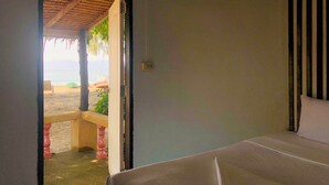 A room with a bed, a view of a beach, and a thatched roof structure outside. -  The Relax Beach Resort (Ko Pha-ngan)