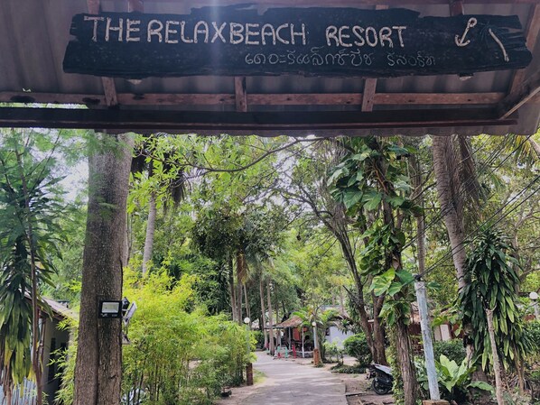 A sign for The RelaxBeach Resort with a pathway leading through a lush, green environment. -  The Relax Beach Resort (Ko Pha-ngan)