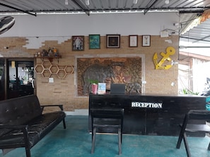 A reception desk with a 'RECEPTION' sign, a laptop, and a computer monitor. There are two black chairs in front of the desk. -  The Relax Beach Resort (Ko Pha-ngan)