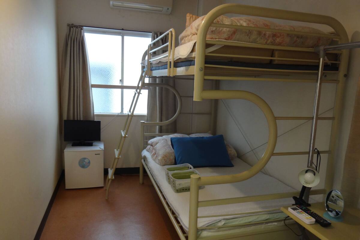 A bunk bed room with a desk, chair, and a television.