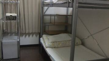 A bunk bed room with a metal frame, a small desk with a chair, and an air conditioning unit on the wall.