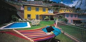 A residential area with a swimming pool, a hammock, and a view of colorful houses.