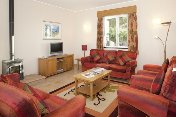 A living room with a sofa set, a wooden coffee table, a television, and a fireplace.