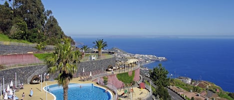 Una piscina cubierta, una piscina al aire libre, sombrillas, tumbonas