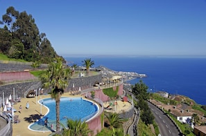 Een binnenzwembad, een buitenzwembad en parasols bij het zwembad