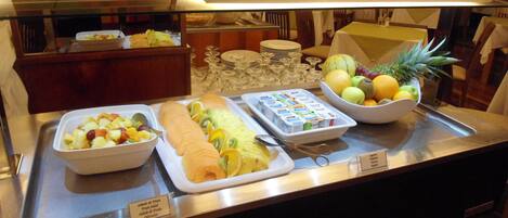 A buffet with various fruits and a salad.
