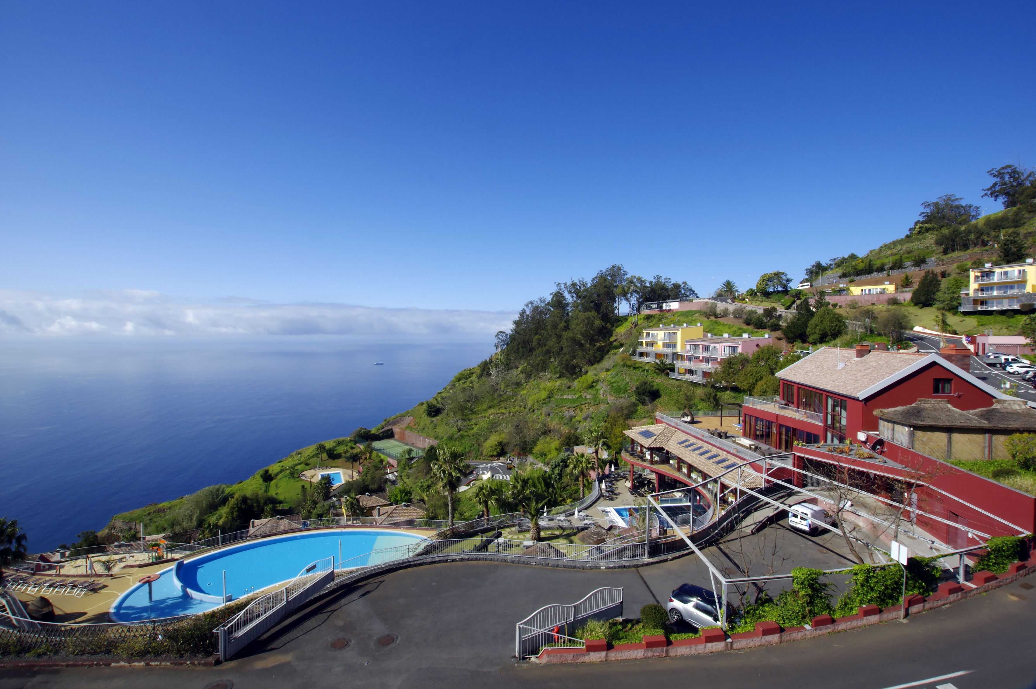 Ein Küstenhotel mit Schwimmbad, ein rotes Gebäude und Meerblick.