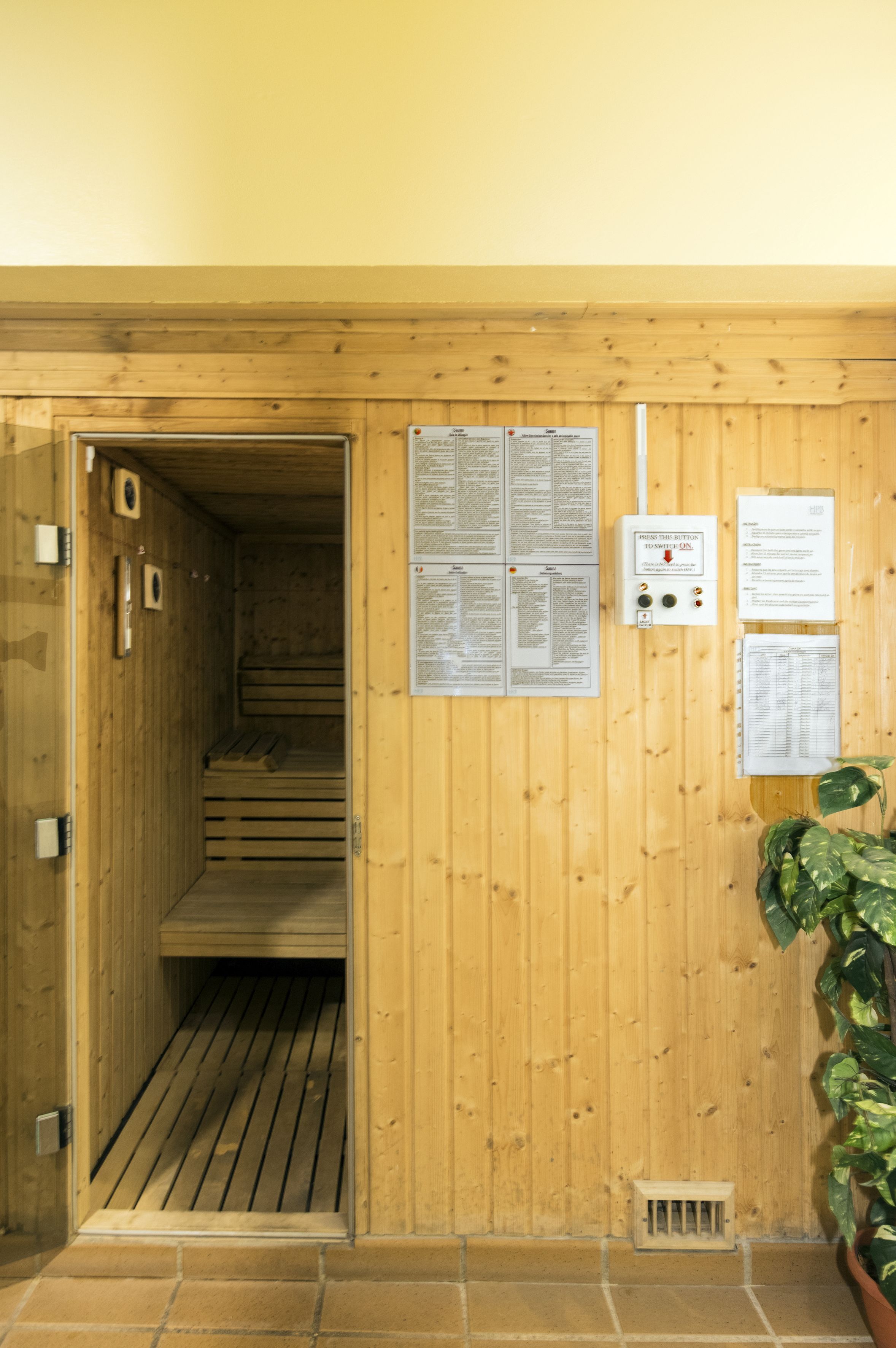 A wooden sauna with a bench, a vent, and informational posters on the wall.