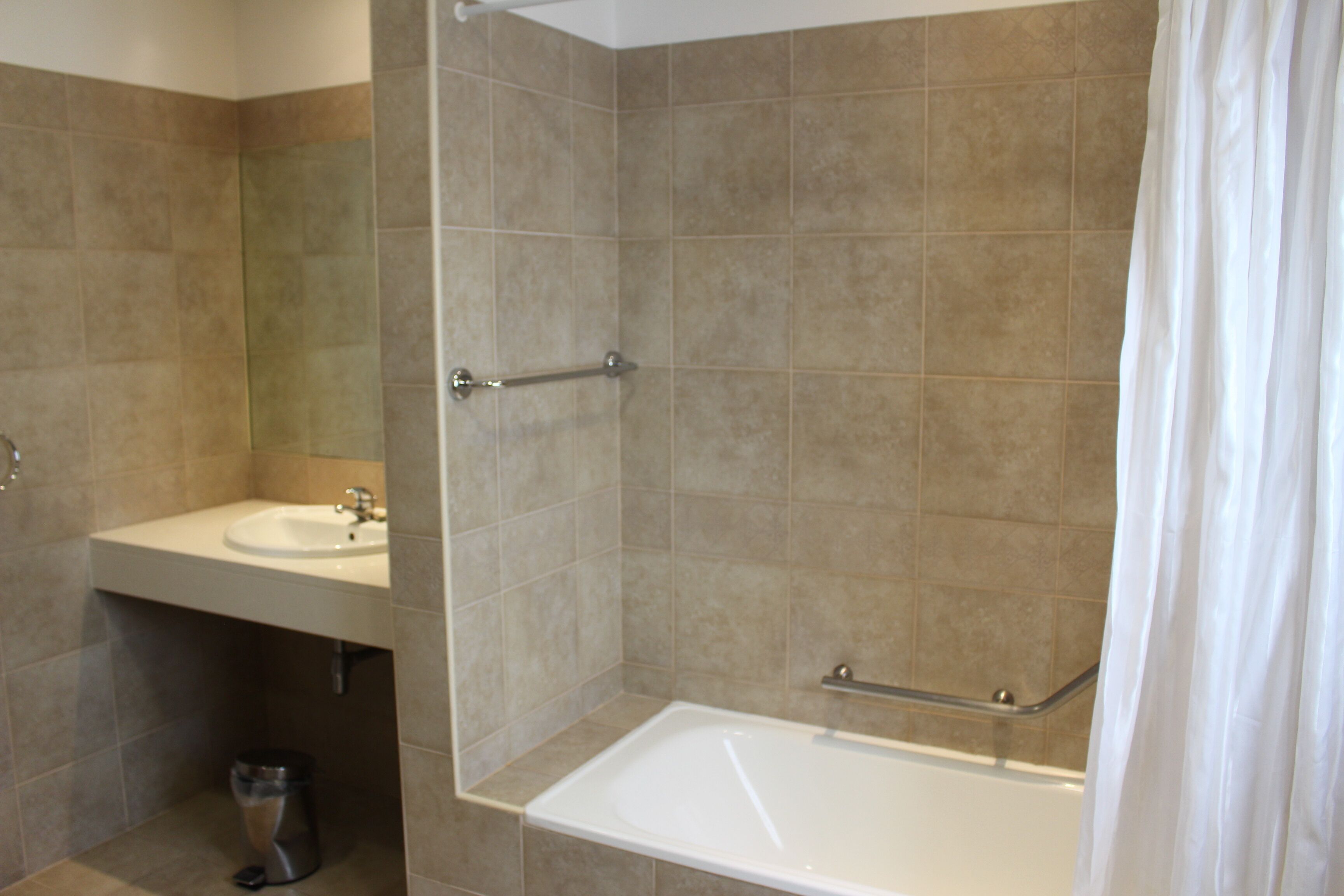 Un baño con bañera, lavamanos y baranda.