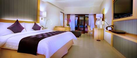 A hotel room with a large bed, a TV, a desk, and a view of the outside.