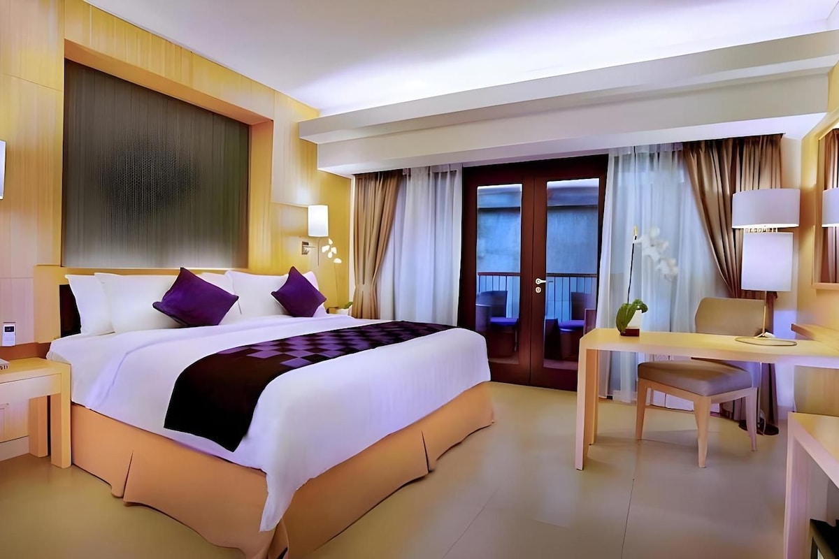 A hotel room with a bed, desk, chair, and a television.