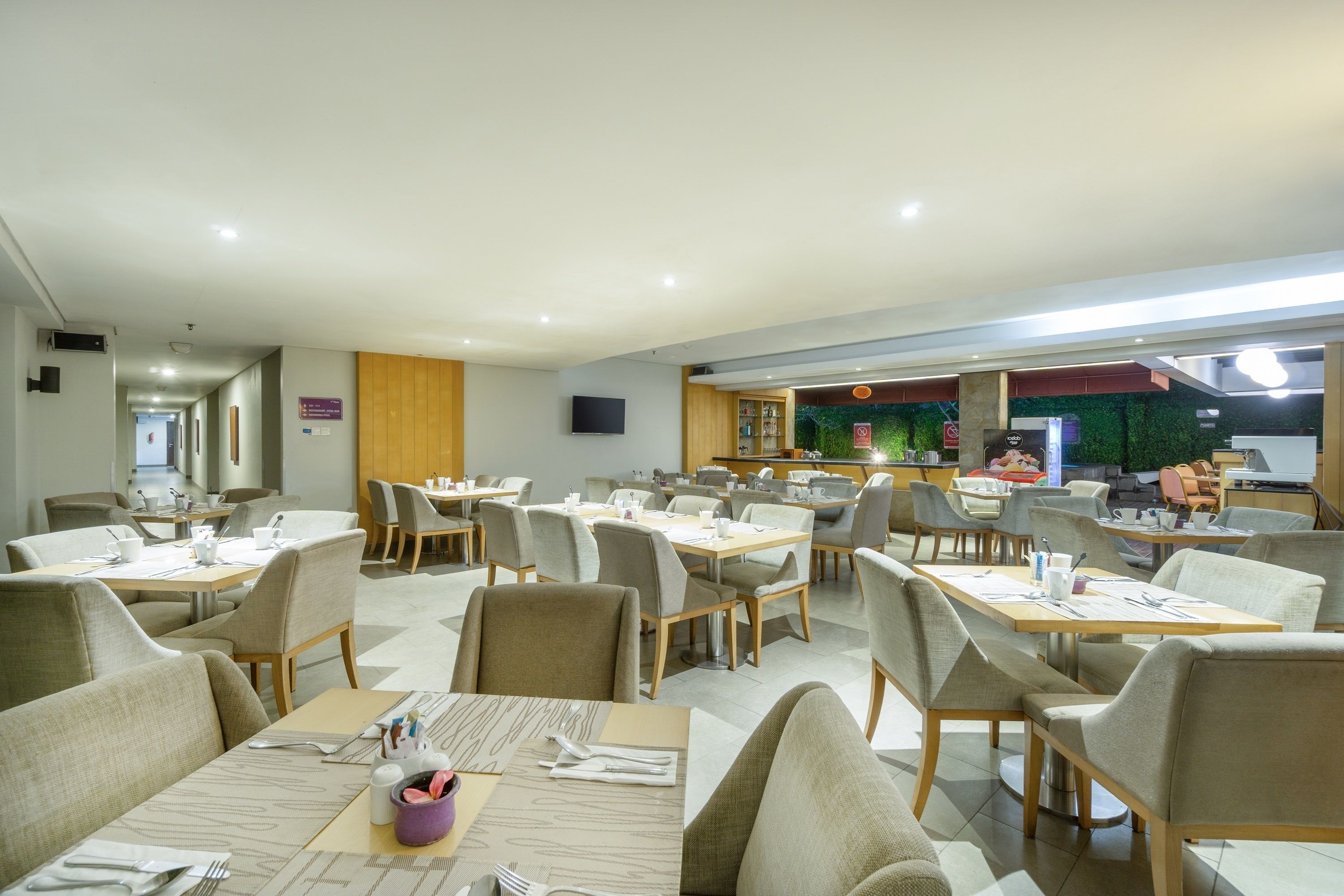 A spacious dining area with multiple tables and chairs, a kitchen area in the background, and a sign indicating a 90% occupancy rate.
