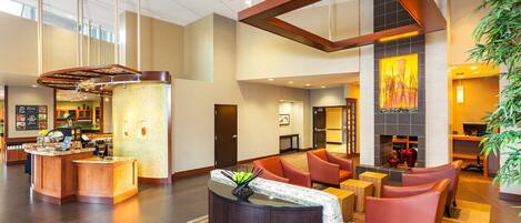 A spacious lobby with a reception desk, seating area, and a fireplace.