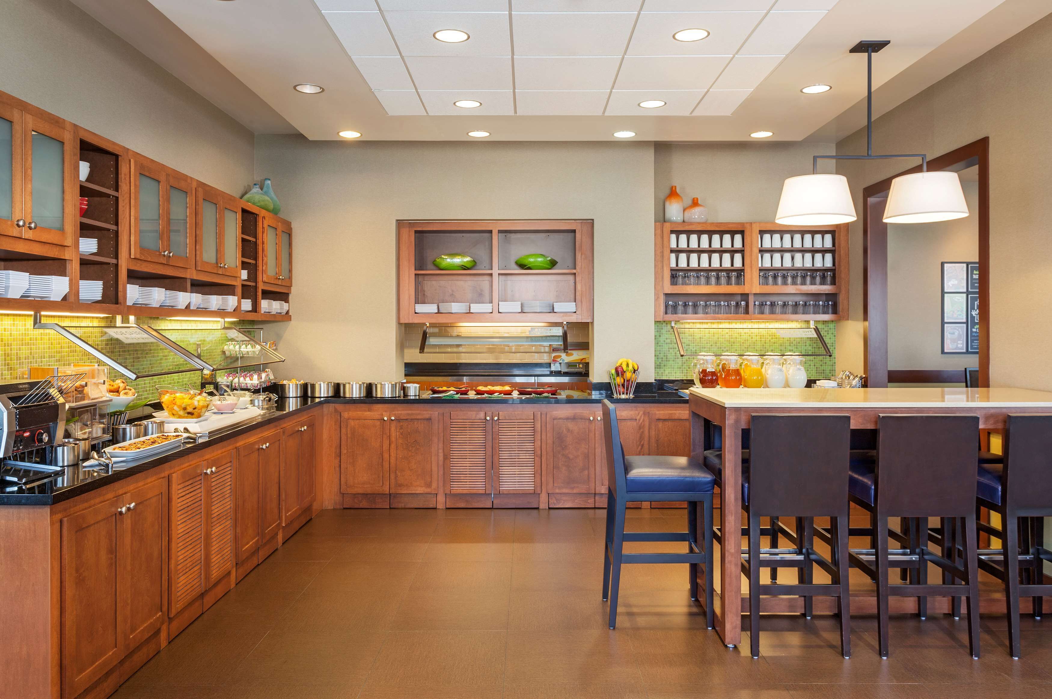A modern kitchen with wooden cabinets, a central island, and bar seating.