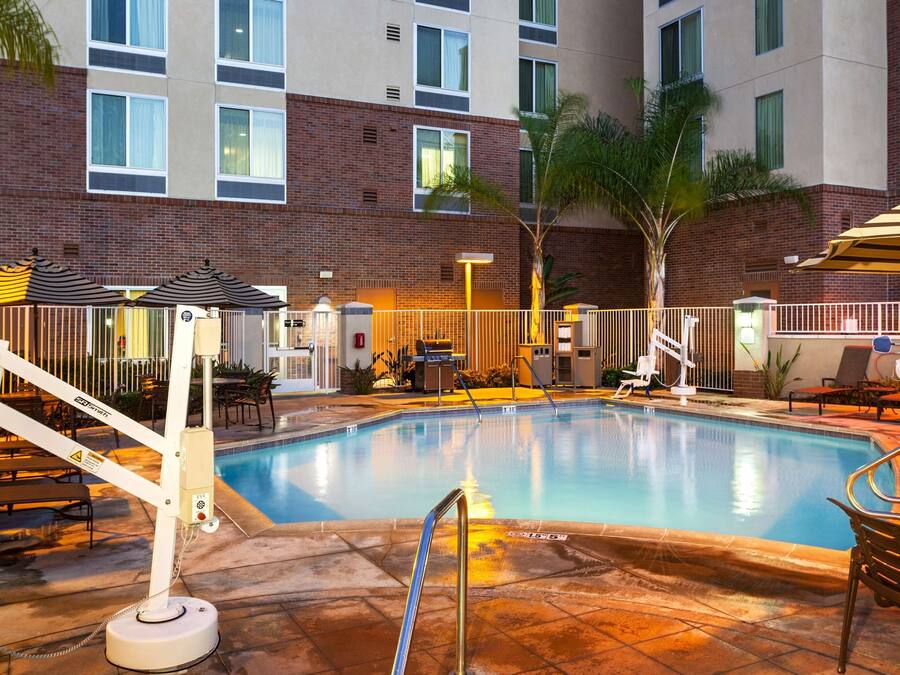 A hotel pool area with a hot tub, lounge chairs, and umbrellas.