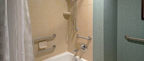A bathroom with a bathtub, grab bars, a showerhead, and a towel rack.