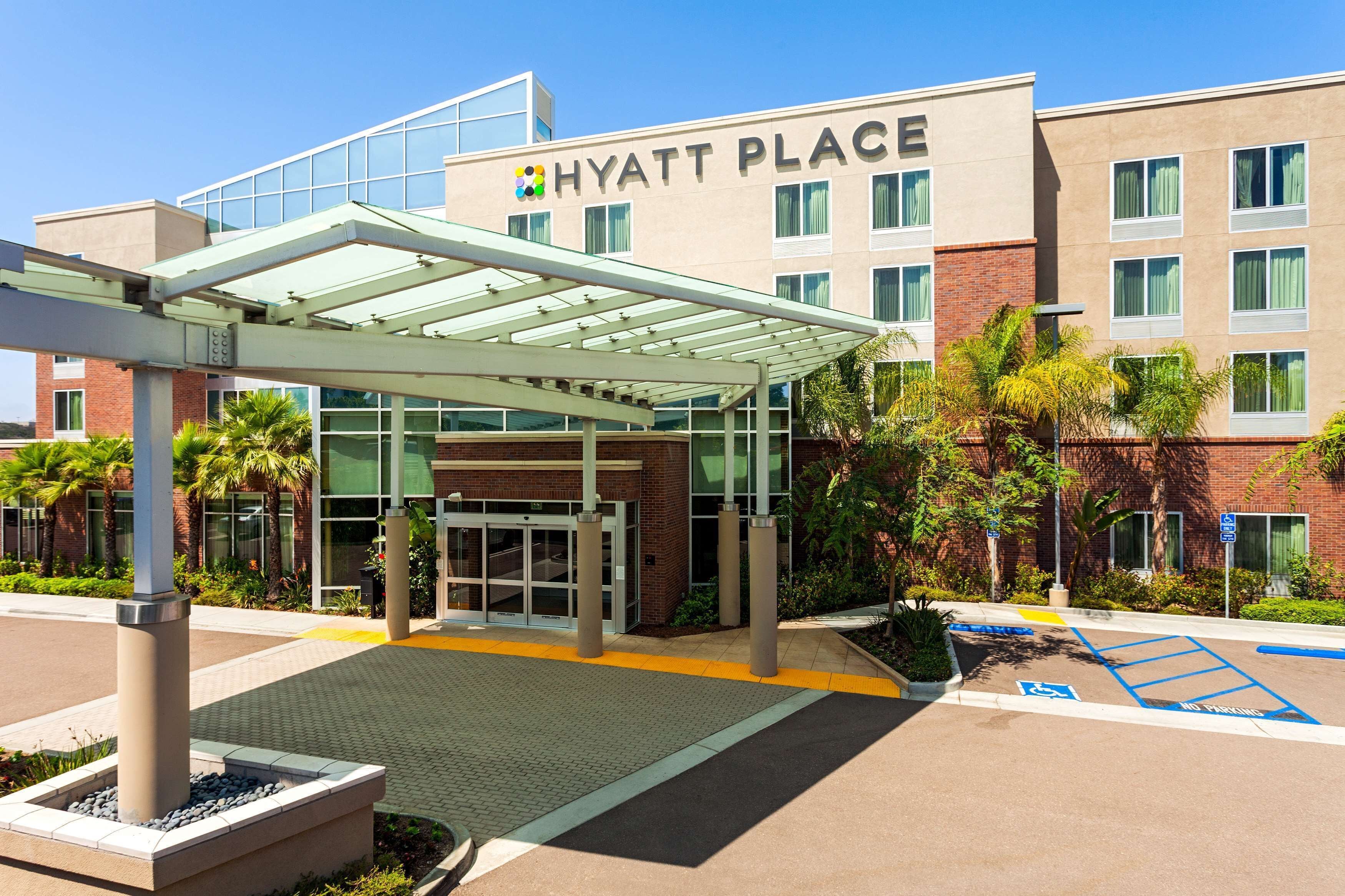 A Hyatt Place hotel entrance with a covered walkway, glass doors, and a parking area with handicapped spaces.