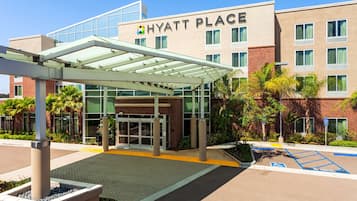 A Hyatt Place hotel entrance with a covered walkway, glass doors, and a parking area with handicapped spaces.