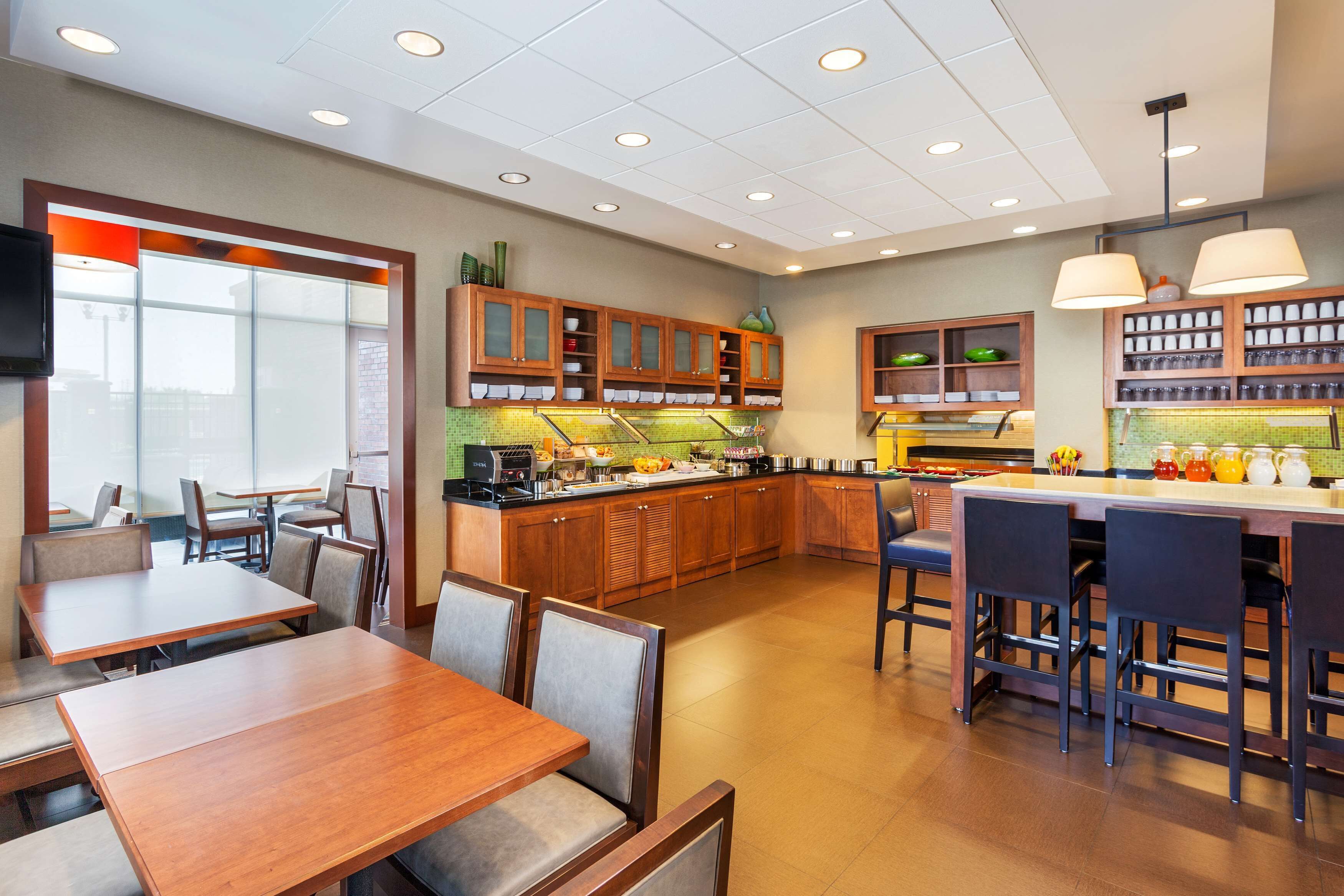 A modern kitchen with wooden cabinets, a central island, and bar seating.