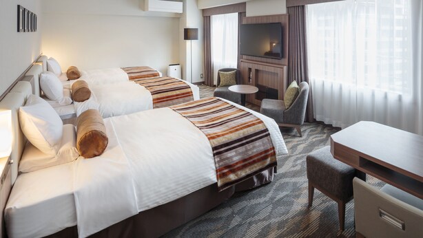 Une chambre d’hôtel avec deux lits, une télévision, un bureau et une chaise.