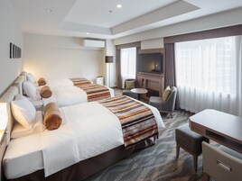 A hotel room with two beds, a TV, a desk, and a chair.