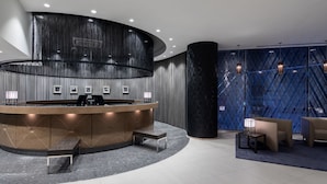 Un espace d’accueil moderne avec un comptoir incurvé, des sièges et un mur orné de motifs.