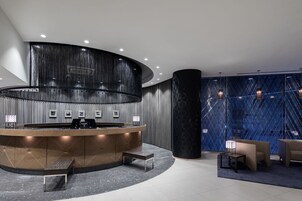 A modern reception area with a curved desk, seating, and a patterned wall.