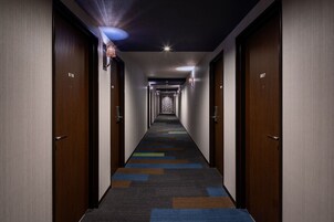 A hotel corridor with wooden doors numbered 807 and 818, a patterned carpet, and recessed ceiling lighting.