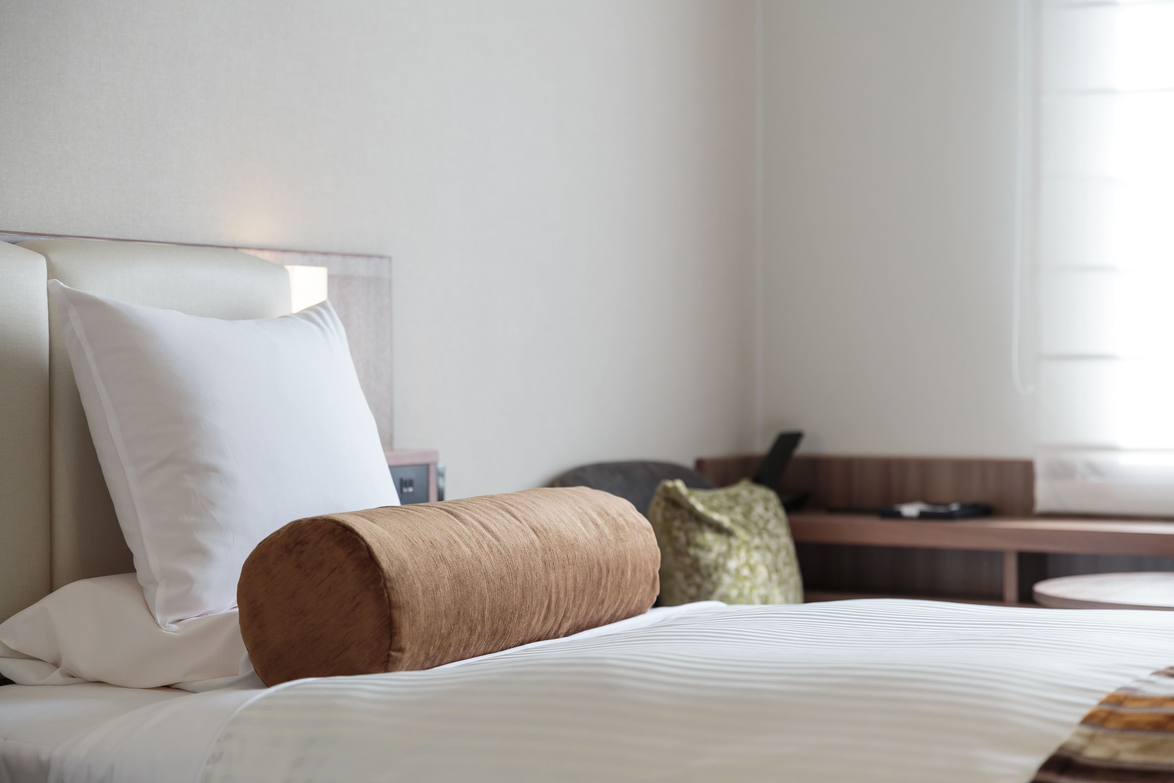 Habitación de hotel con cama, almohadas, cabecero de madera, una mesita y un sofá.