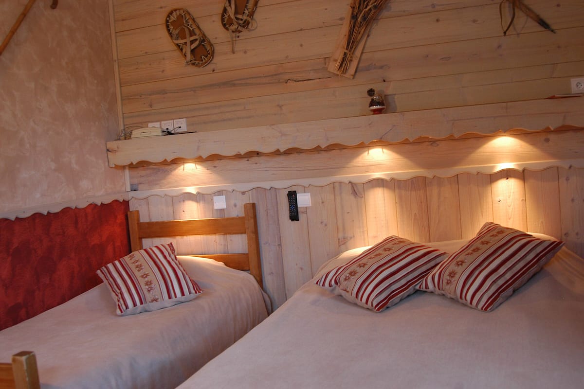 Una habitación acogedora con dos camas, cabeceros de madera y techo de madera decorado con adornos colgantes.