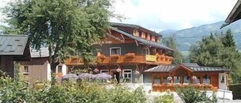 A traditional chalet-style building with a sloped roof, wooden exterior, and a balcony.