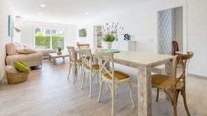 Een moderne woonkamer met een bank, salontafel en een eethoek met stoelen en een houten tafel.
