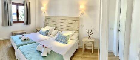 A double room with two beds, a wooden headboard, bedside tables, and a window with curtains.