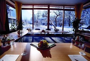 Een restaurant met uitzicht op een besneeuwd landschap door grote ramen.