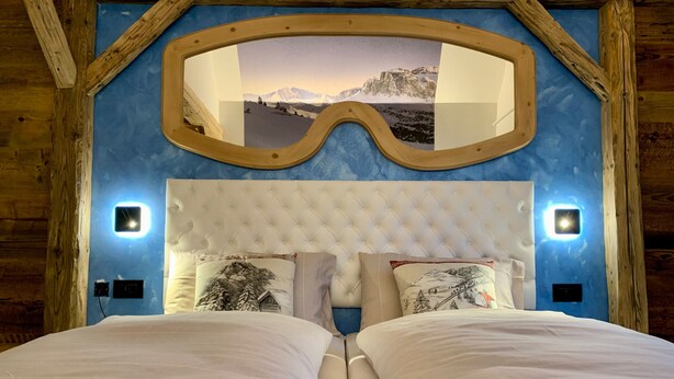 Ein Schlafzimmer mit großem Spiegel, zwei Betten und Blick auf die Berge.